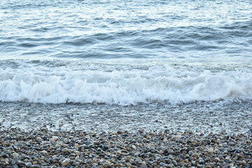 foaming water at the shore consisting of small pebbles