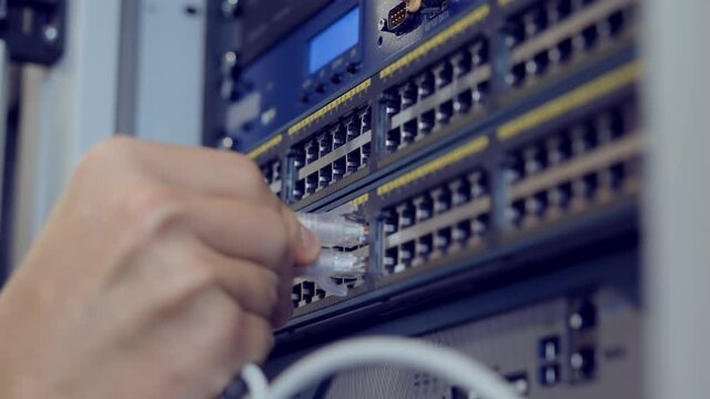 IT Engineer Patching Network Equipment In Server Room.Network Engineer Maintenance Work In Server Room .IT Technician Works With Ware And Cables in Big Data Center.Connecting Lan Cable To Mainframe