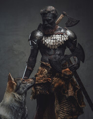 Handsome and evil guardian holding a double axe standing with a wolf