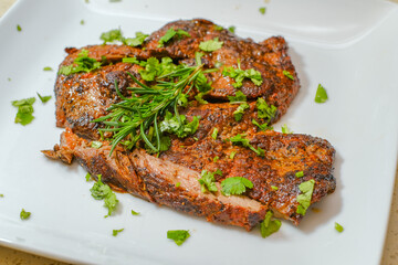 Marinated steak sliced in pieces with cilantro in a cutting board