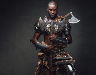 Medieval black skinned warrior with axes staring at camera in dark background