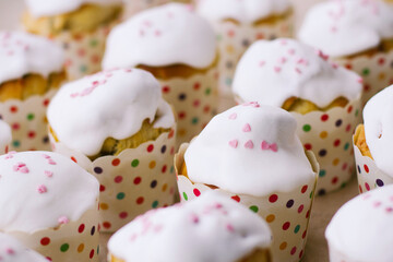 small Easter cakes in paper wrappers with colorful polka dots stand in straight rows