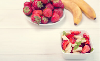 Banana strawberry salad cut into slices with mint leaves. Vitamin breakfast.