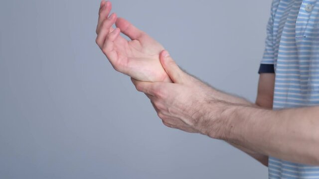man holds herself by the brush and feels severe pain. male arms holding his painful wrist caused by prolonged work on the computer, laptop. video stock footage. Slow motion
