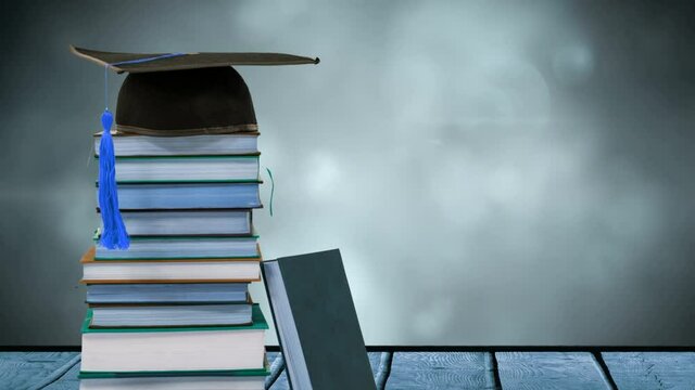 Animation of stack of books with graduation hat on top over glowing lights