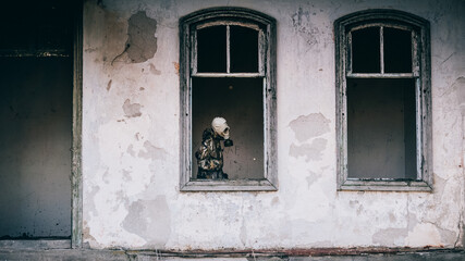 A man in a gas mask in the window of a destroyed house - a post-apocalyptic image of the future in...