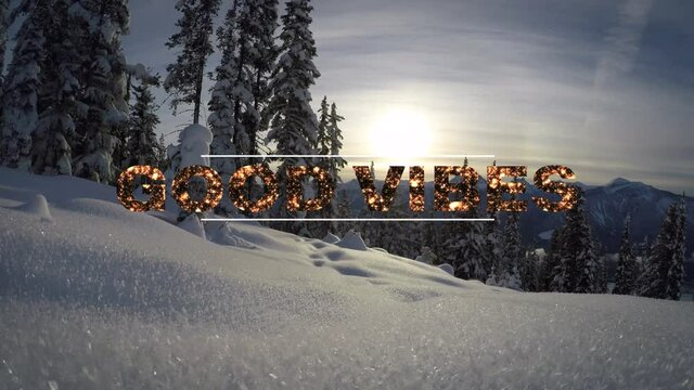 Animation of the words good vibes written in gold letters over sunlit snow covered forest