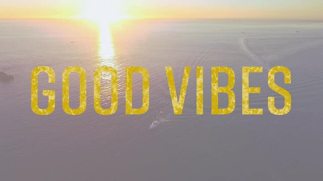 Animation of the words good vibes written in yellow letters with sun setting over tranquil sea