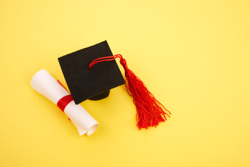 Academic hat with diploma on yellow background. Graduation theme