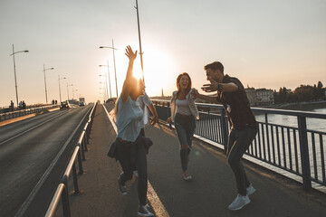 Group of friends hangout at the city street.They walking over the bridge and joying in sunset.	
