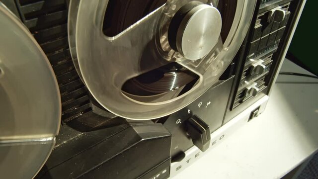 Tape recorder started by hand, stopping and rewinding magnetic deck, closeup view