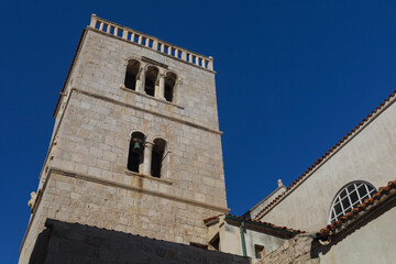 Fototapeta premium Old catholic church in historical centre of ancient Pag city with blue sky above, Croatia