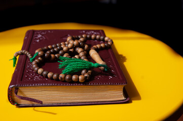 holy book and rosary on yellow background