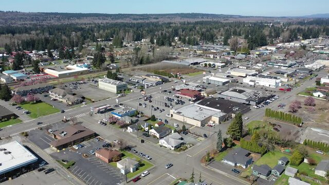 Orbiting cinematic aerial drone shot of downtown Marysville, by the I-5 freeway, a distant suburb, bedroom community North of Seattle on the shores of Puget Sound in Washington