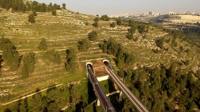 Modern Passenger Train enter Jerusalem Mountain tunnel and Cityscape, Aerial
, drone view from Jerusalem Israel April 2021
