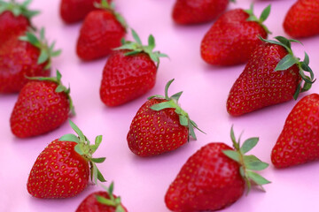 Fresh strawberries organized on pink background. Selective focus.