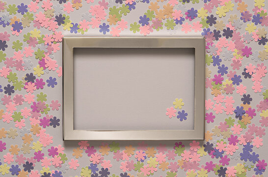 Empty picture frame with artificial flowers in pastel colors.Top view with copy space.Greeting card.