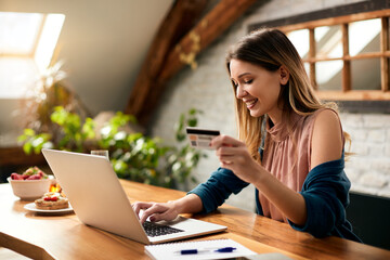 Young happy woman e-shopping with credit card and laptop at home.