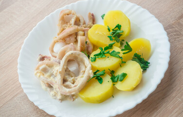 Squid in creamy garlic sauce with potatoes on a white plate, delicious seafood dinner in 10 minutes