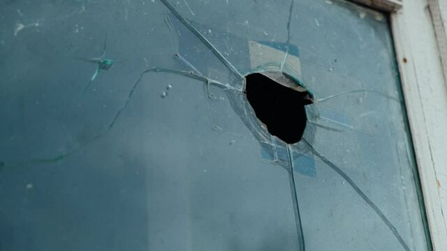 Hole in the broken window. Broken showcase in old building. Wooden white window frame. Hole and cracks around. Hooligans broke the glass with a stone. Vandalism. Protest actions. Close-up. Sad Picture