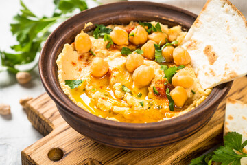Hummus with olive oil and paprika at light kitchen table.
