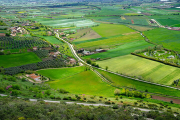 A stunning landscape of southern Italy from a high hill, Madonna del Granato Sanctuary, in April, when the fields emerge green. The valley is lined with roads, many trees, shrubs and houses