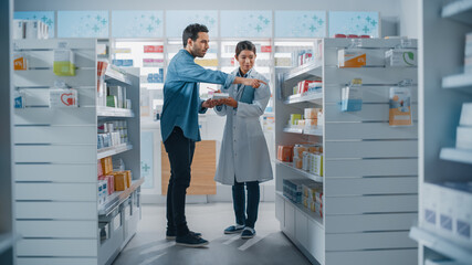 Naklejka na ściany i meble Pharmacy Drugstore: Female Asian Pharmacist Helping Latin Male Customer with Recommendation, and Advice to Buy Medicine, Drugs, Vitamins. Modern Pharma Store Shelves with Health Care Products