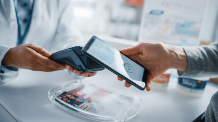Comptoir de caisse de pharmacie de pharmacie : pharmacien et client utilisant un smartphone NFC avec terminal de paiement sans contact pour acheter des médicaments sur ordonnance, des produits de santé. Photo en gros plan