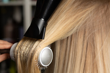 Fototapeta premium Hairdresser drying and straightening client's hair