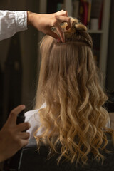 Fototapeta premium Hair stylist making curls in a beauty salon