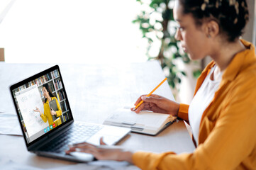 Distance learning, online lecture. African American female student studying at home using a laptop,...