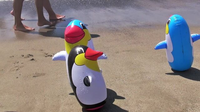 A boy at the beach playing with some inflatable toys floating or always standing up if hit. 