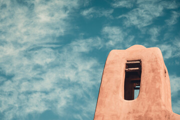Tower of an old historic adobe church in New Mexico with a painterly sky