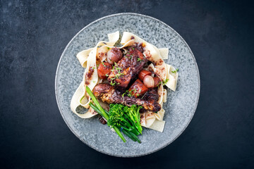 Modern style traditional French coq au vin with vegetable marinated in Burgundy sauce as top view in a design plate