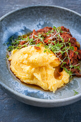 Traditional barbecue wagyu pulled beef with Italian polenta and herbs served as close-up on a Nordic design bowl