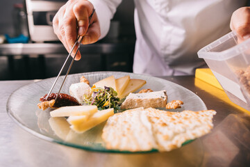 Chef decorates a cheese plate with tweezers