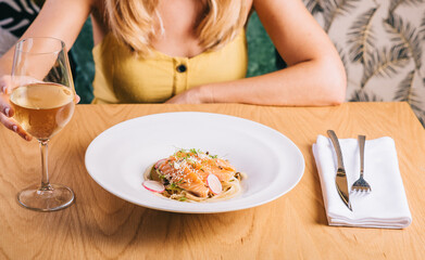 Obraz na płótnie Canvas spaghetti with salmon on the background girl with a glass of white wine