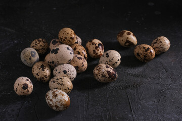 Obraz premium Small quail eggs are scattered on a dark background under the concrete, close-up. High quality photo