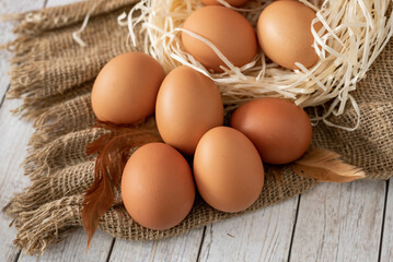 close-up of fresh farm eggs lying in the nest, on sacking with feathers.