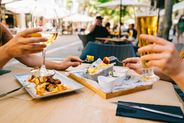a glass of beer and wine on a table with dishes two girls have lunch together in a restaurant on the terrace