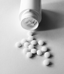 White bottle of white pills overturned on the table