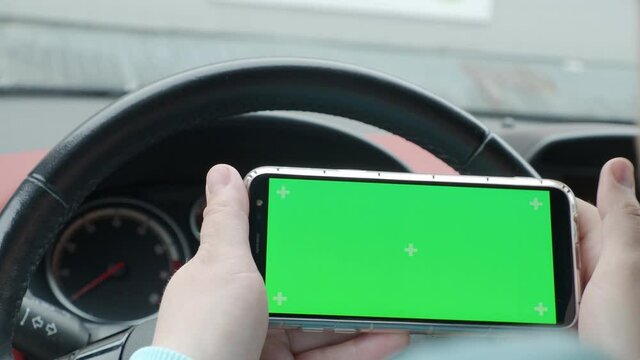 A Man In A Car Holding A Phone Green Screen