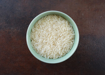 Uncooked Jasmine Rice in a Green Bowl against a Brown Background