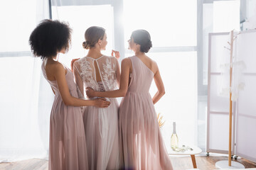 elegant bridesmaids hugging young bride on sunny morning at home.