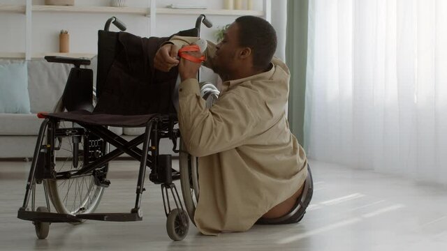 Disabled Man Trying To Get In Wheelchair Lying Indoor