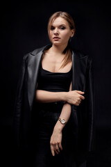 A beautiful, stylish young woman in a sporty black top with a gold wristwatch. He looks at the camera. Black background.