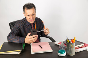Business man at working desk holding eyeglasses worry about a phone call, photo on white background.