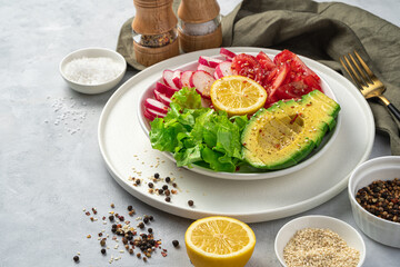 Fresh, vegetable salad with avocado on a gray background.