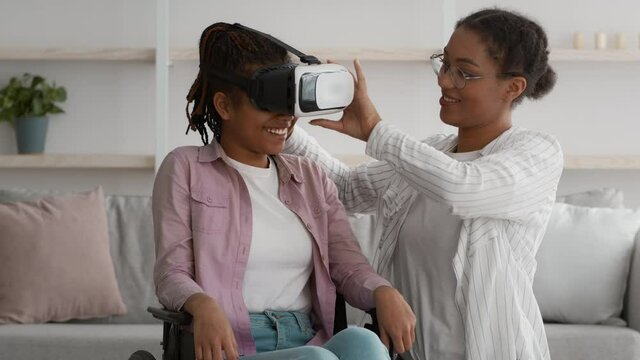 Happy Handicapped African Girl In Wheelchair Experiencing Augmented Reality Indoor