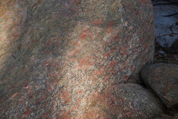Large granite stone boulder of dark brown color. Close-up on a granite texture. Stone with rounded...